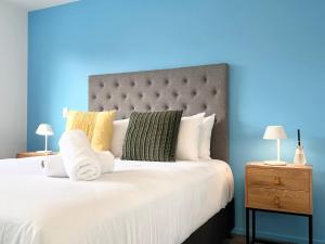 a bedroom with a large bed with a blue background at New 3 Storey luxe townhouse on quiet street in Christchurch