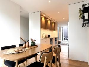 a kitchen and dining room with a wooden table and chairs at Lux Achi-Design Townhouse park view in Latimer Sq in Christchurch