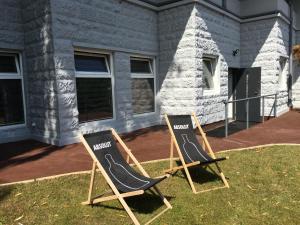 two chairs sitting in the grass in front of a house at Panorama Gdynia Rooms in Gdynia