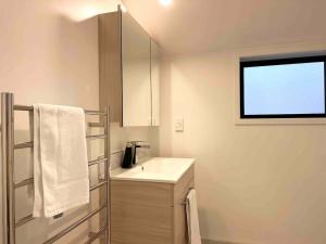 a white bathroom with a sink and a window at Little Cutie on Worcester Quiet Stylish in Christchurch +15 photos