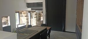 eine Küche mit Spüle und Theke mit Stühlen in der Unterkunft Cottage au cœur de l'Aubrac in Saint-Chély-dʼAubrac