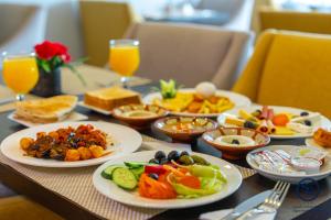 a table with plates of food and glasses of orange juice at Signature Guest Hotel in Jeddah