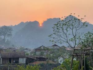 a sunset over a village with a mountain in the background at Homestay Mộc Bản in Hữu Lũng +1 photo