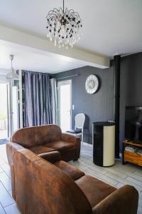 a living room with leather furniture and a chandelier at Les Bleuets - Erdivines in Erdeven