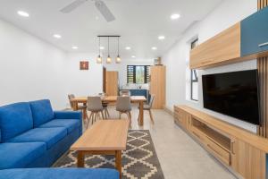 Una sala de estar con un sofá azul y un televisor. en Serenity Suites 3 - Appartement 2 Chambres Luxueux Toit-Terrasse, en Cap Malheureux