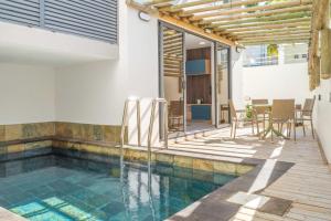Una piscina con una mesa y sillas al lado de una casa. en Serenity Suites 3 - Appartement 2 Chambres Luxueux Toit-Terrasse, en Cap Malheureux