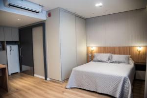 una camera con letto e frigorifero di Apartamentos sofisticados no coração do Batel a Curitiba