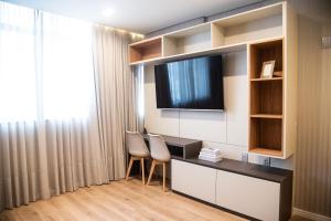 una camera con scrivania, 2 sedie e TV di Apartamentos sofisticados no coração do Batel a Curitiba