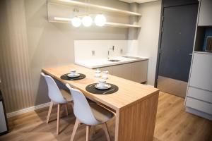 una cucina con un tavolo di legno e sedie bianche di Apartamentos sofisticados no coração do Batel a Curitiba Altre 20 foto