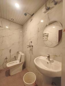 a bathroom with a sink and a toilet and a mirror at Raja Palace in Ayodhya