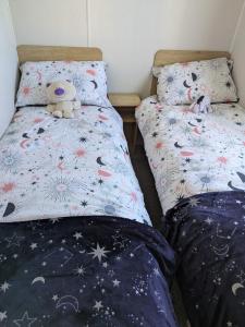 two twin beds with teddy bears sitting on them at Seascape Caravan in Kinmel Bay