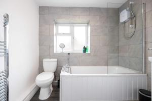 a bathroom with a tub and a toilet and a sink at Bright and Modern 2 Bed Home w Garden in Liverpool in Liverpool