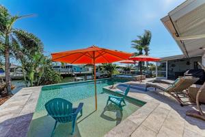 a swimming pool with chairs and an umbrella at Forget Me Knot in Bradenton