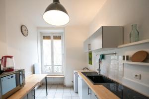 Una cocina con gabinetes blancos y un reloj en la pared. en Appartement de charme dans le 6e - central, en Gare des Brotteaux 20 fotos más