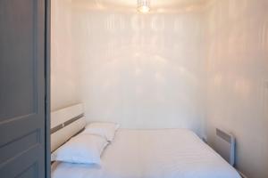 Un dormitorio pequeño con una cama blanca con dos almohadas. en Appartement de charme dans le 6e - central, en Gare des Brotteaux