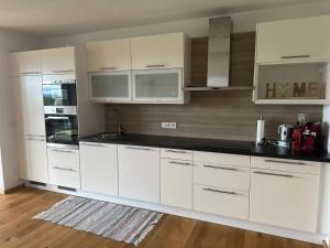 a kitchen with white cabinets and black counter tops at Apartment Postplattler in Hof bei Salzburg