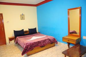 een slaapkamer met een bed en een spiegel bij Hotel Zaraa in Ooty