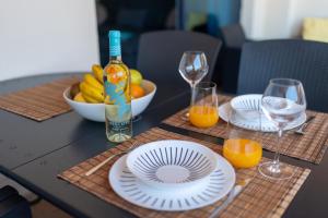 a table with plates and glasses and a bowl of fruit at El Teide Apartment with Pool & Balcony in Puerto de Santiago +41 photos