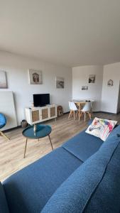 a living room with a blue couch and a table at Beau Front de mer cosy accès direct plage St aubin sur mer in Bernières-sur-Mer +7 photos