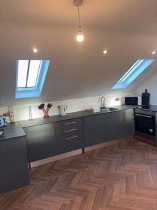 eine Küche mit schwarzen Schränken und einem Holzboden in der Unterkunft The Chapel Annex,Northumberland  + 6 Fotos