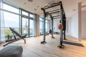 a gym with treadmills and ellipticals in a room with windows at ScanHotels City in Rostock