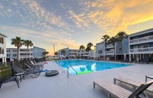 a swimming pool with chaises and chairs in a resort at Sea Oats B106 by ALBVR - Pet Friendly - Great renovation and tons of space in this condo - Outdoor Pools, Pier, and Dedicated Beach Access in Gulf Shores