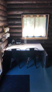 a table with chairs in a room with a window at Le Shed - 2 personnes in Saint-Siméon