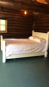 a bedroom with a white bed in a log cabin at Le Shed - 2 personnes in Saint-Siméon