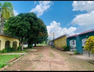 a dirt road between two buildings with a tree at Casa COP 30 BELÉM-Mosqueiro in Belém