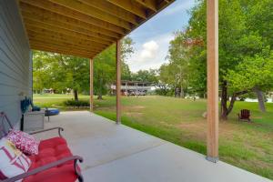 a porch with a red couch and a view of a park at Cozy Casita and Cabana on Lake Marble Falls! in Cottonwood Shores +21 photos