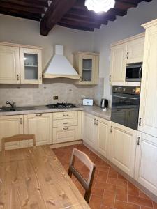 a kitchen with white cabinets and a table and a stove at Casa Pieve in Lucca