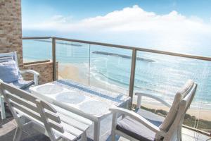 a balcony with a table and chairs and the ocean at Beachfront Bliss 3 bedroom Privacy in Netanya
