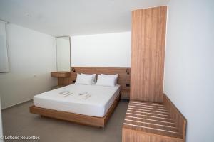 Un dormitorio con una cama con sábanas blancas y almohadas blancas. en Rodos Suites on the Park, en Rodas