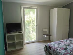 a bedroom with a bed and a tv and a window at Petit Brunò in Monfalcone