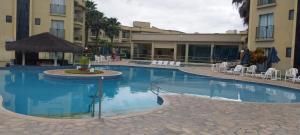 a pool at a hotel with chairs and tables at Flat Quartier - Aldeia das Águas in Barra do Piraí