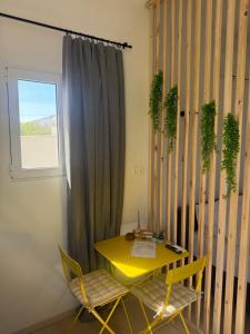 a yellow table and chairs in a room with a window at LaLaLa Cosy Studio in Koutsourás