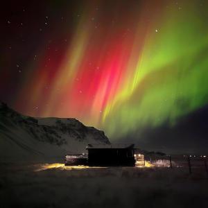 an aurora in the sky over a building at Sky Retreat & Private Jacuzzi in Hvolsvöllur