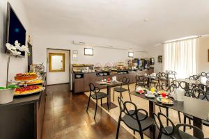 a dining room with tables and chairs and a kitchen at Hotel Des Artistes Roma in Rome