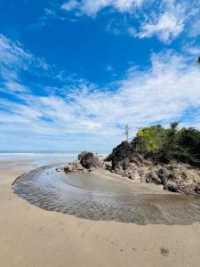 a sandy beach with a rocky island in the ocean at Posada Cachalote in Panguí