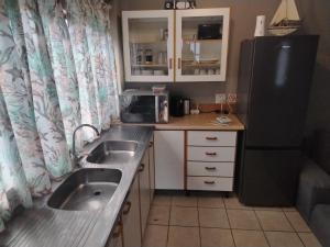 a small kitchen with a sink and a refrigerator at Puravida guesthouse in Umkomaas