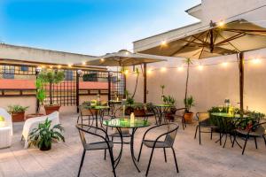 an outdoor patio with tables and chairs and umbrellas at Hotel Des Artistes Roma in Rome