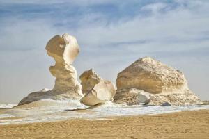 a group of rocks on a sandy beach at White & Black Desert Camping in Az Zabū
