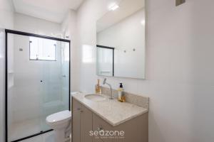 a bathroom with a sink and a toilet and a mirror at Apto c/ Churrasqueira próx. da Praia SMO0202 in Itajubá +10 photos