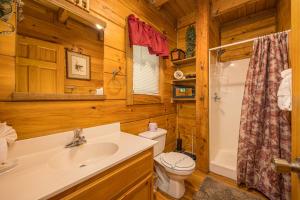 a bathroom with a sink and a toilet in a log cabin at Wild At Heart Wears Valley by American Patriot Getaways in Hatchertown