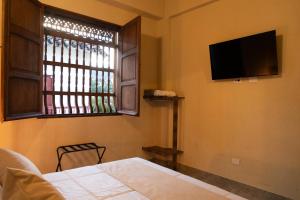 a bedroom with a bed and a tv and a window at Hotel Boutique Lomas Colonial in Santa Fe de Antioquia