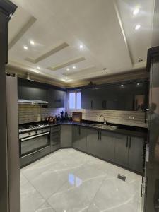 a large kitchen with gray cabinets and a white tile floor at شقق فندقية بالقاهره in Banī Ghālib