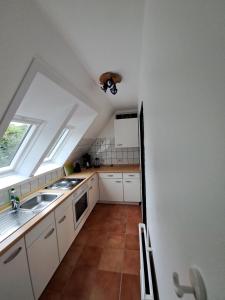 a kitchen with white cabinets and a sink and a window at Ferienwohnung-1-Nei-Stich-19a in Norddorf +9 photos