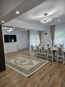 Zimmer mit einem Tisch und Stühlen sowie einem Flachbild-TV in der Unterkunft Vila veverita in Schitu-Tarcău
