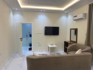 a living room with a couch and a tv on the wall at شقق الضباب 1 in Al Baha