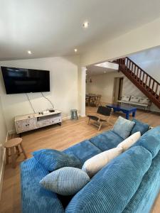 Una sala de estar con un sofá azul y un televisor. en Le Jardin des Sables avec piscine - 10 voyageurs, en Saint-Paul